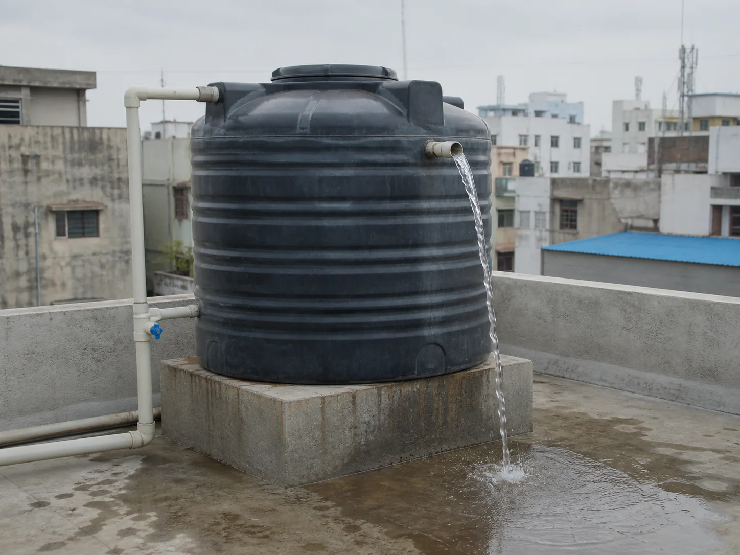 Water flowing from a real overflow outlet on a full rooftop water tank